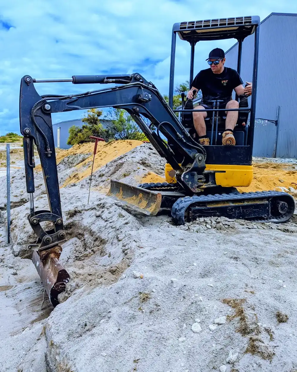 Kim operating a mini excavator on a coastal site